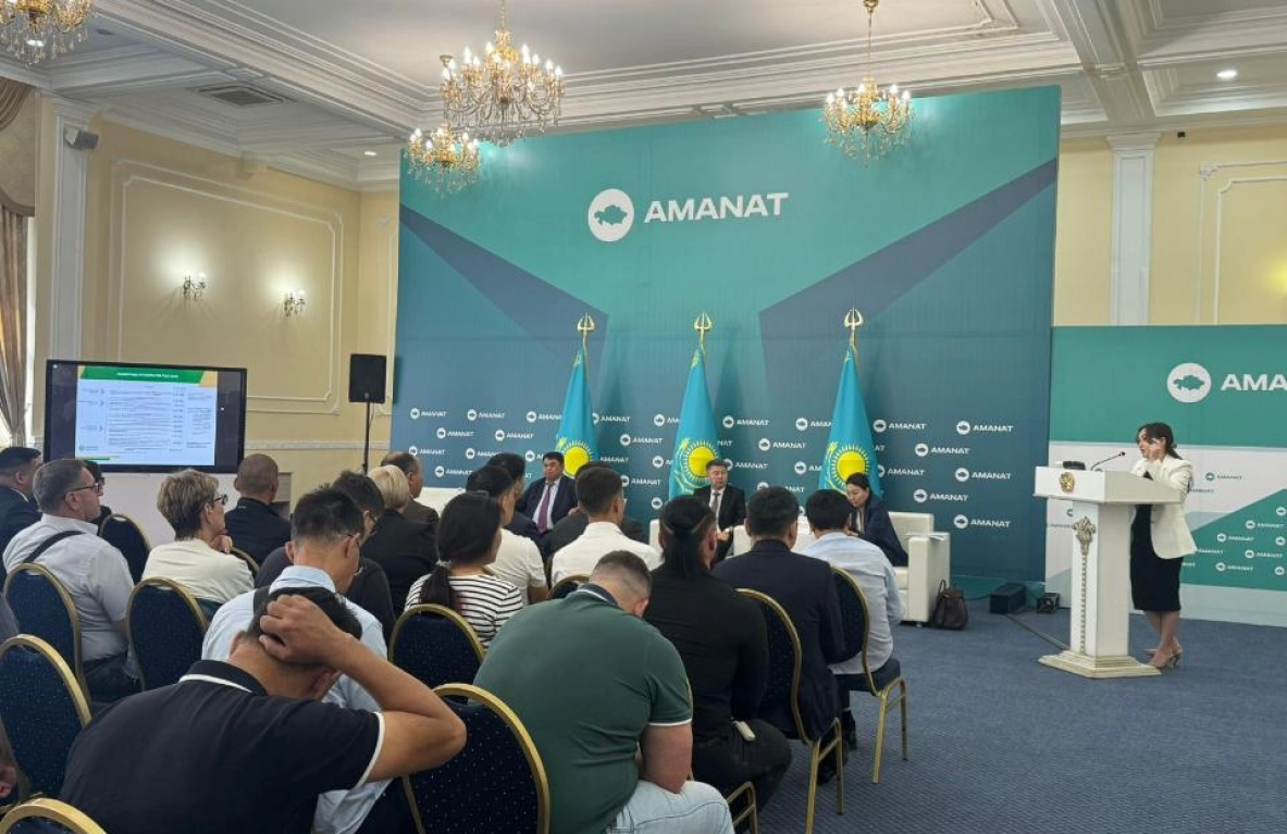 A woman addresses a seated audience at an Amanat presentation. - МЭКС